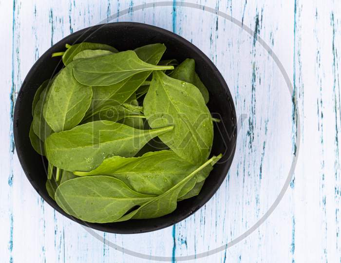 Top View Of Fresh Green Spinach Leaves In Wooden Bowl
