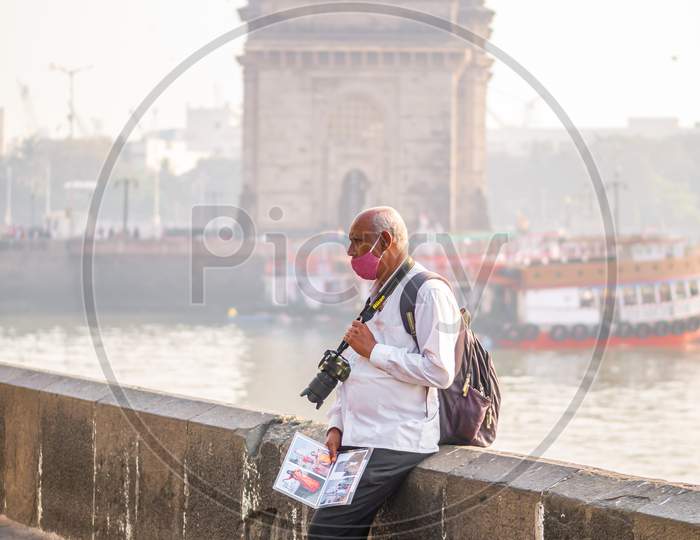 Unidentified Photographer Man Wearing A Face Mask Relating To Covid-19 Or Coronavirus Outbreak Near The Gateway Of India, A Famous Tourist Place In Mumbai