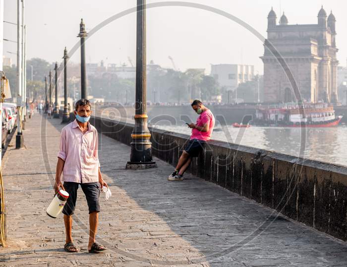Unidentified Man Wearing A Face Mask Relating To Covid-19 Or Coronavirus Outbreak And Selling Tea Near The Gateway Of India, A Famous Tourist Place In Mumbai