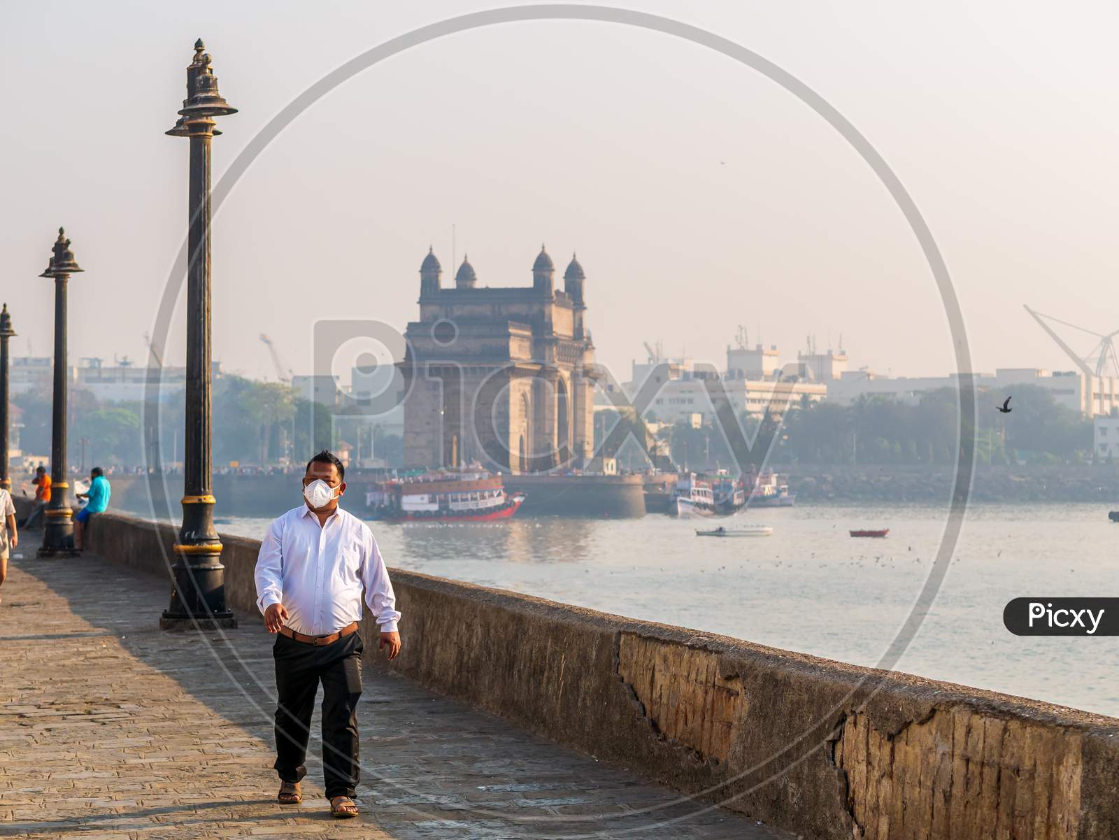 Unidentified Man Wearing A Face Mask Relating To Covid-19 Or Coronavirus Outbreak Near The Gateway Of India, A Famous Tourist Place In Mumbai