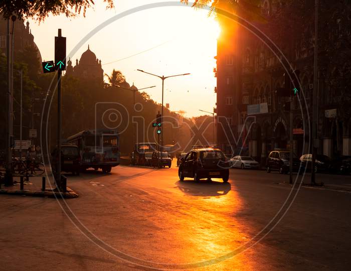 Silhouette Of Mumbai Taxi With Sun Rising In Background And Traffic Signal In Green On The Streets Of Mumbai