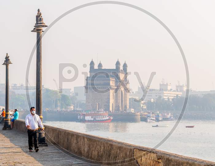 Unidentified Man Wearing A Face Mask Relating To Covid-19 Or Coronavirus Outbreak Near The Gateway Of India, A Famous Tourist Place In Mumbai