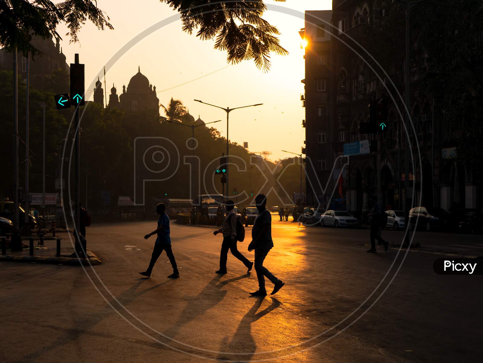 Silhouette Of People Crossing Streets With The Sun Rising In Background And Traffic Signal In Green On The Streets Of Mumbai