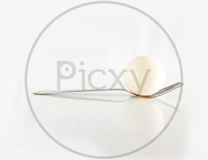 An Egg Picked Up In A Fork On Top Of A White Cloth