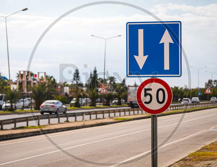 Several Road Signs: Speed Limit Within 50 Km Per Hour And Regulation Of Traffic In Lanes In The Background Of A Motorway With Trees