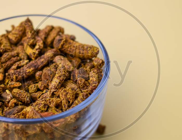 Selective focus closeup of a glass of dried turmeric carnation spices