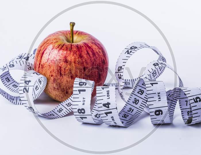 Red Apple Wrap By White Measuring Tape To Measure Length On A White Background, Diet, Healthy Lifestyle Stock Photo