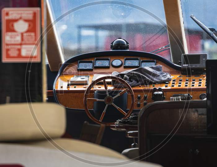 View Of The Varnished Wooden Steering Wheel Of A Marine Yacht, Control Devices, Gauges, Buttons And Direction Arrows
