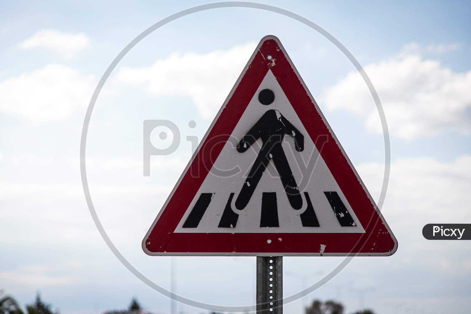 Pedestrian Crossing Road Sign In A Triangular Shape On A Blue Sky Background