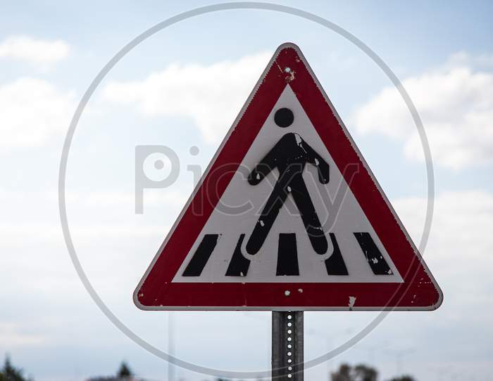 Pedestrian Crossing Road Sign In A Triangular Shape On A Blue Sky Background