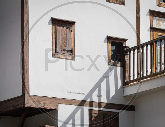Close-Up Wall Of A White Stone House With Wooden Windows And Shutters. Old European Architecture