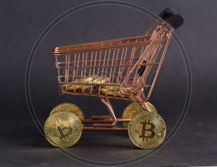Bitcoins In Shopping Cart. Black Background Stock Photo