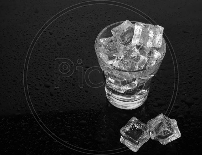 Chilled Glass Of Water Filled With Ice On Black Waterdrops Background