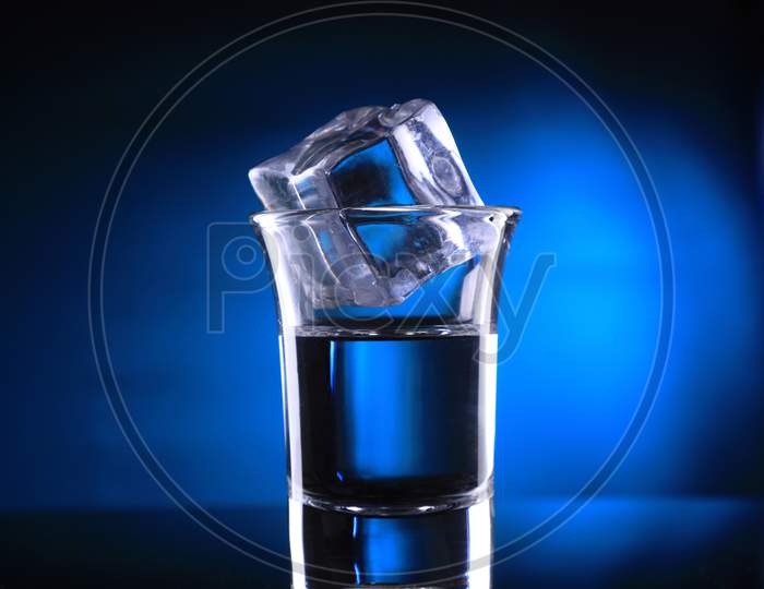 Shot Glass With An Ice Cube On Blue Background