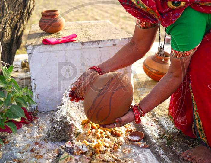 Religious Female Offering Water From Clay Pot To Lord Shiva Statue In A Temple. Women Offering Prayer To God.