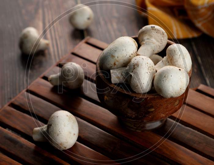 Fresh Uncooked Organic Button Mushrooms In A Wooden Bowl