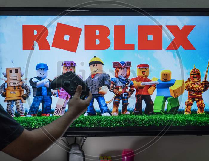 Man With A Controller Standing In Front Of A Pc Console Tv Screen With A Steam Controller Playing Popular Free To Play Game Roblox