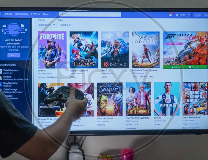 Man Holding A Steam Remote In Front Of A Pc Console Screen Showing Twitch Streaming Platform Base Screen With Games Where People Are Streaming Fulltime To Earn Money