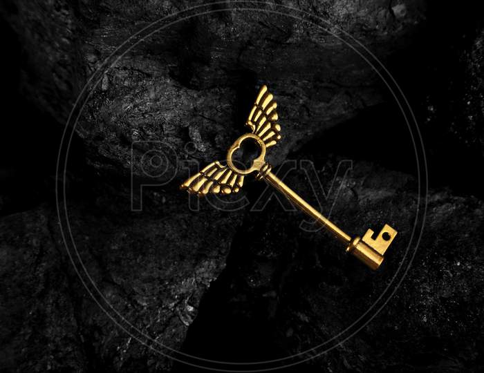 Golden Antique Key With Wings On Dark Black Background
