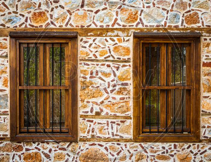 Close-Up Wall Of A Stone House With Wooden Windows And Shutters. Old European Architecture