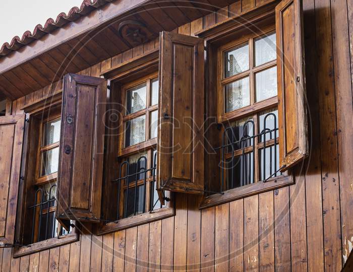 Close-Up Wall Of A Wooden House With Wooden Windows And Shutters. Old European Architecture