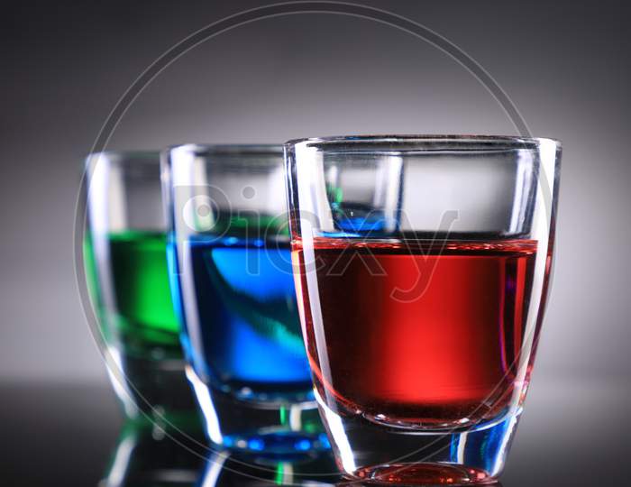 Three Colorful Shot Glasses On Grey Background