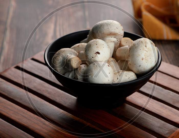 Fresh Uncooked Organic Button Mushrooms In A Black Bowl