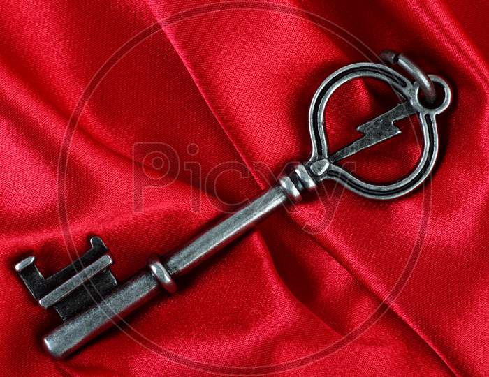 Old Vintage Key In Red Satin Cloth Background