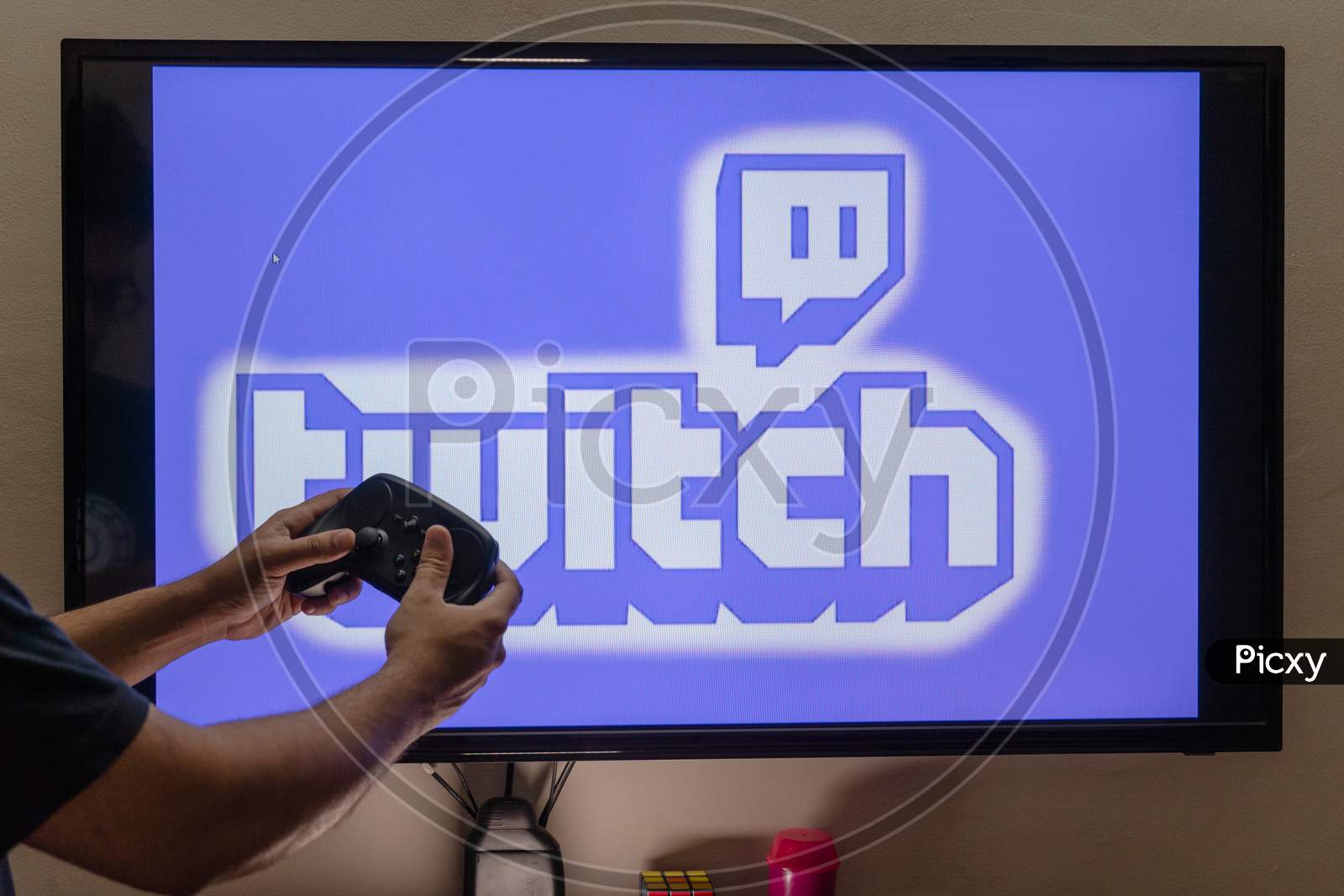 Man Holding A Steam Remote In Front Of A Pc Console Screen Showing Twitch Streaming Platform Where People Are Streaming Fulltime To Earn Money