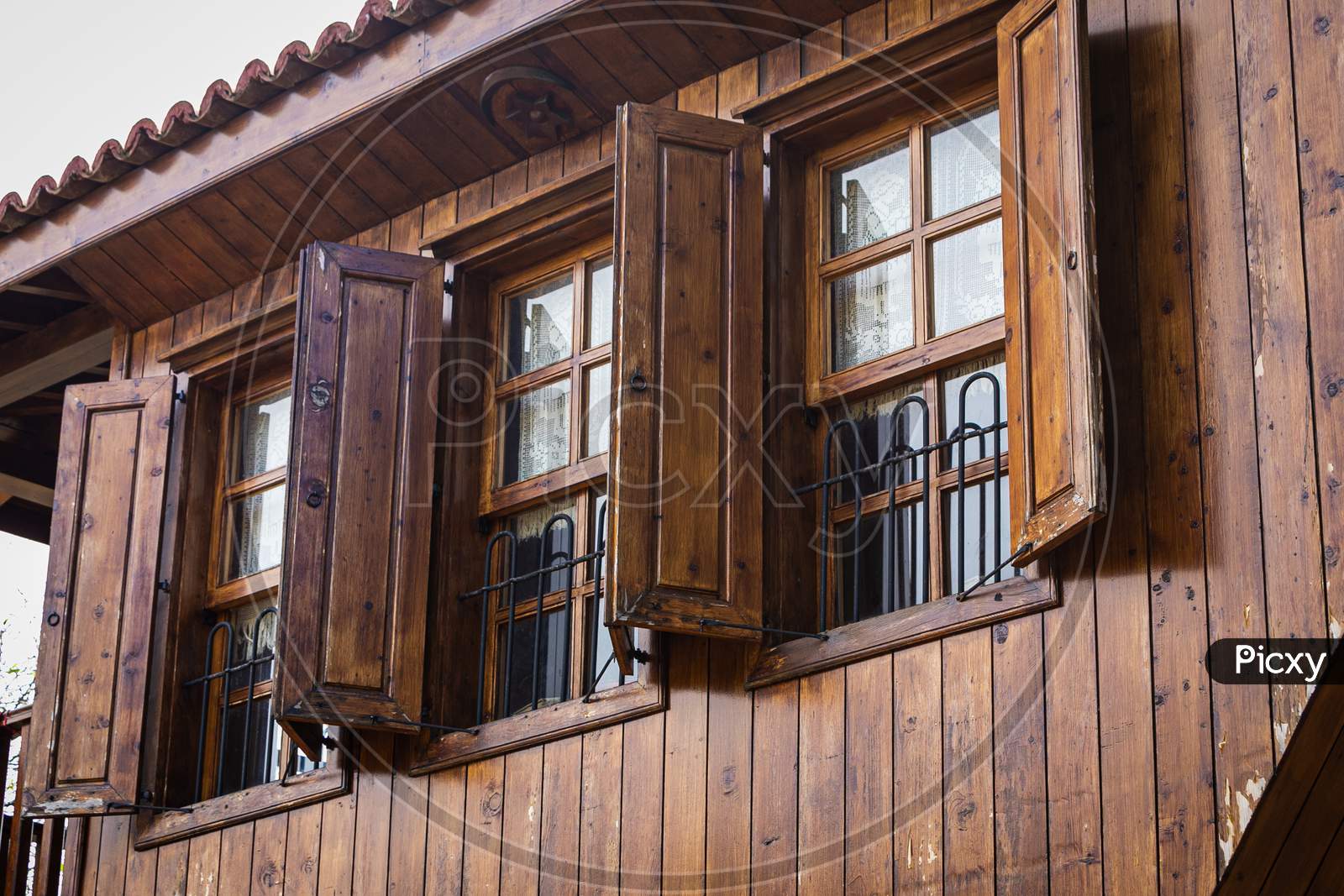 Close-Up Wall Of A Wooden House With Wooden Windows And Shutters. Old European Architecture