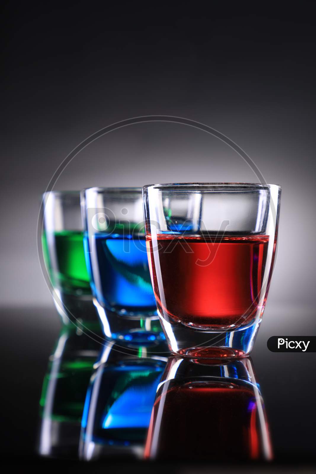 Three Colorful Shot Glasses On Grey Background