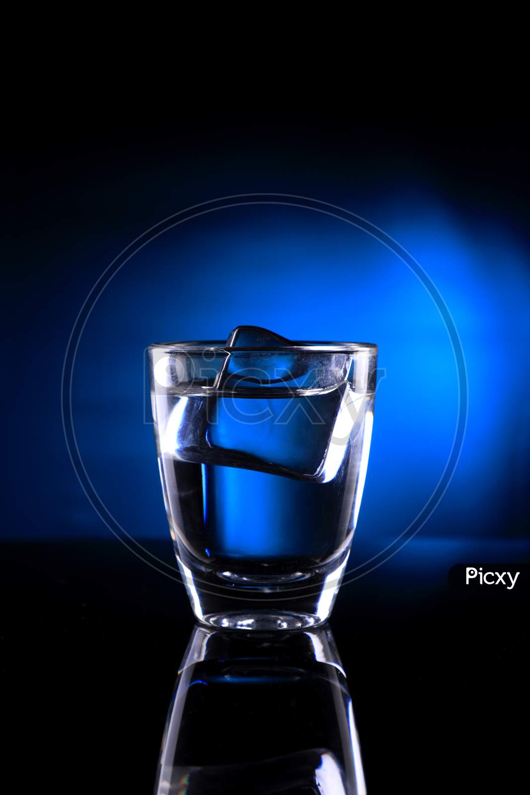 Shot Glass With An Ice Cube On Blue Background