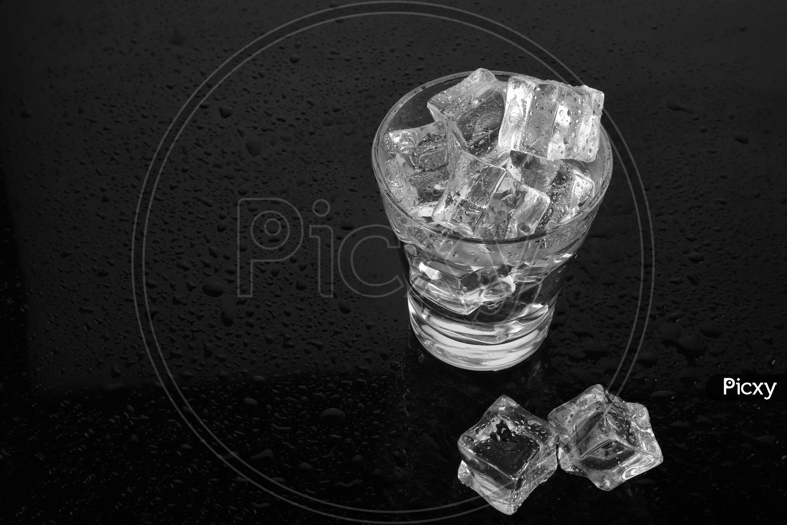 Chilled Glass Of Water Filled With Ice On Black Waterdrops Background
