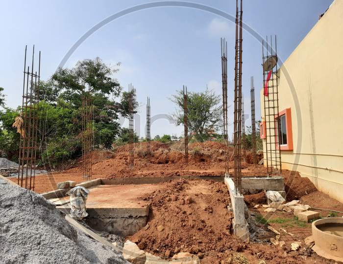A Closeup of residential building foundation construction and soil is filled inside the foundation, iron rods for column