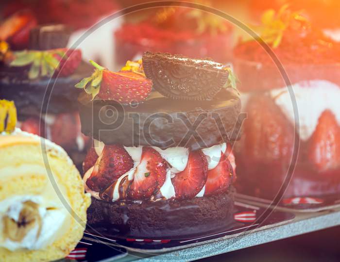 Close-Up Of Chocolate Brownie With Cream Filling, Strawberries And Puff Pastry