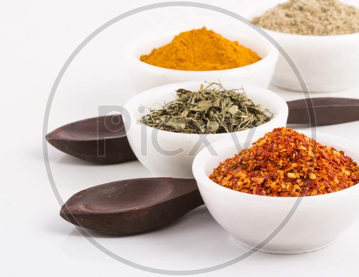 Various Spices In Ceramic Bowls With Wooden Spoons Isolated On White Background. Stock Photo