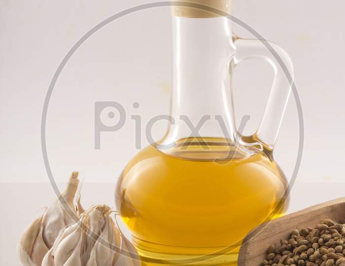 Garlic With Essential Oil In A Glass Jar Wooden Spoon On White Background Stock Photo