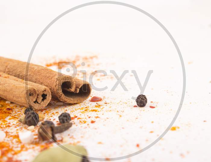 Spices: Turmeric, Chilly Powder, Cardamom And Cinnamon  On Ground With White Background Stock Photo