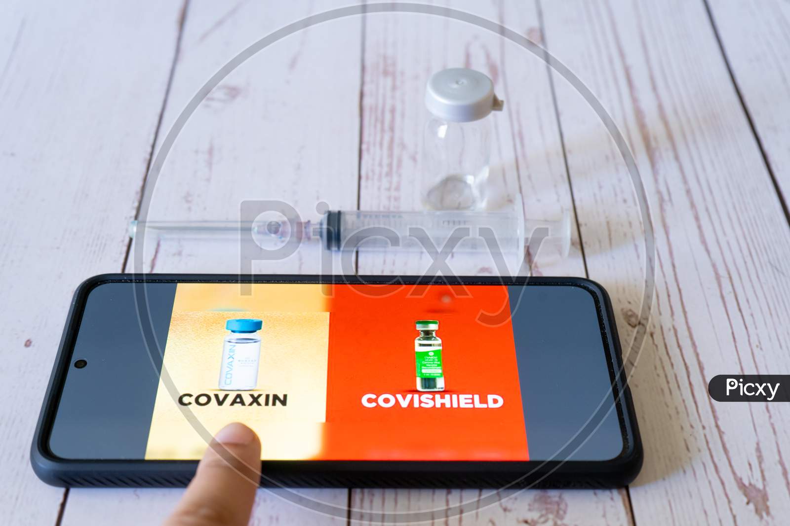 Mobile Phone Showing The Covid 19 Coronavirus Vaccines Covishield Covaxin For Selection In The Co-Win App With Syringe And Vial On The Side