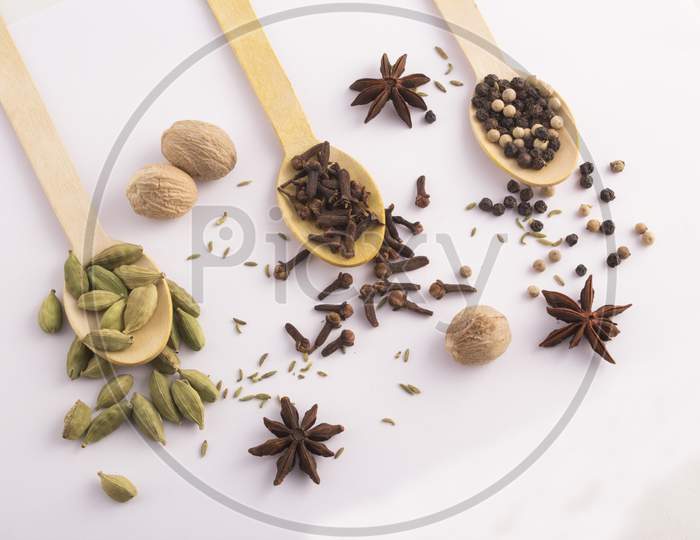 Wooden Spoons With Cloves, Cardamom  And Black Peppercorns Top View Stock Photo