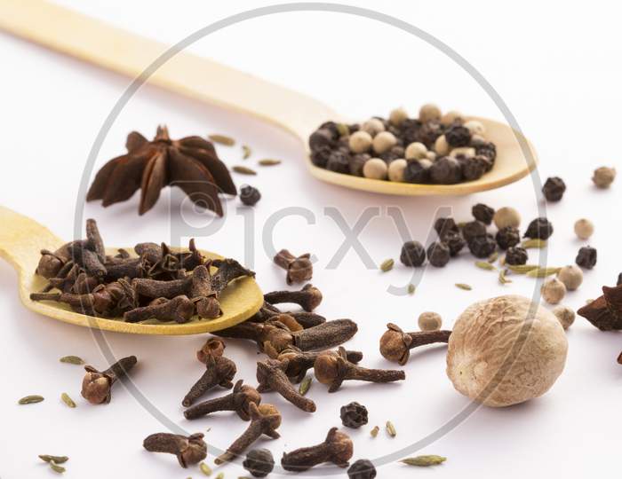 Wooden Spoon With Cloves And Black Peppercorns Side Stock Photo