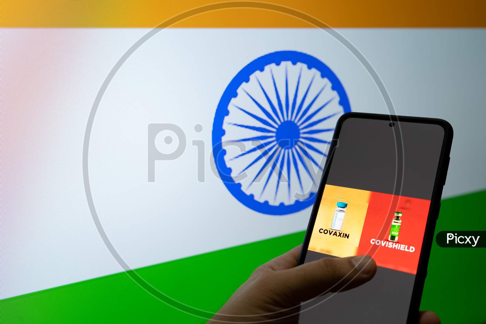 Man Holding A Mobile Phone Selecting Covaxin And Covishield In Front Of India Flag As Innoculation Against The Covid 19 Coronavirus Pandemic