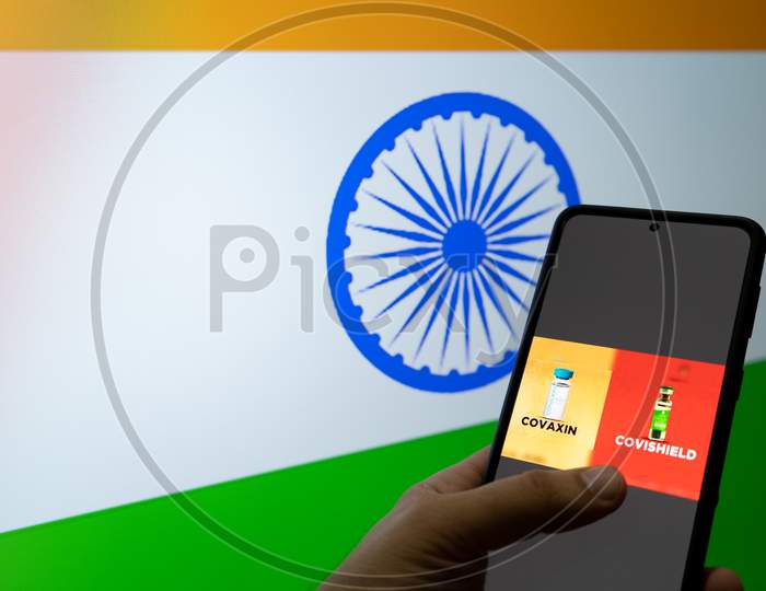 Man Holding A Mobile Phone Selecting Covaxin And Covishield In Front Of India Flag As Innoculation Against The Covid 19 Coronavirus Pandemic