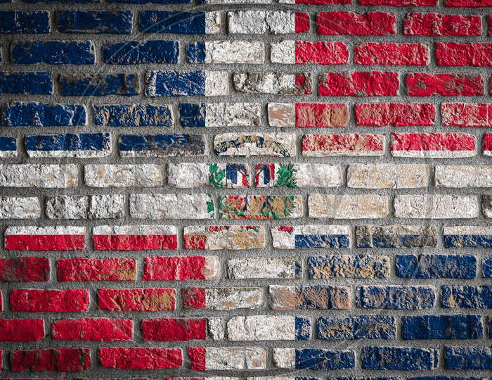 National Flag Of Dominicana Depicting In Paint Colors On An Old Brick Wall. Flag  Banner On Brick Wall Background.
