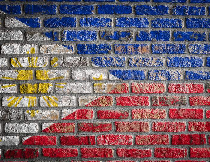 National Flag Of Philippines Depicting In Paint Colors On An Old Brick Wall. Flag  Banner On Brick Wall Background.