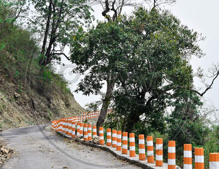 Asphalt Road On The Hill With Trees And Protective Pillars