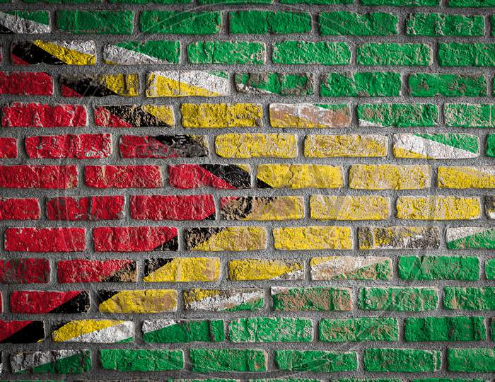 National Flag Of Guyana Depicting In Paint Colors On An Old Brick Wall. Flag  Banner On Brick Wall Background.