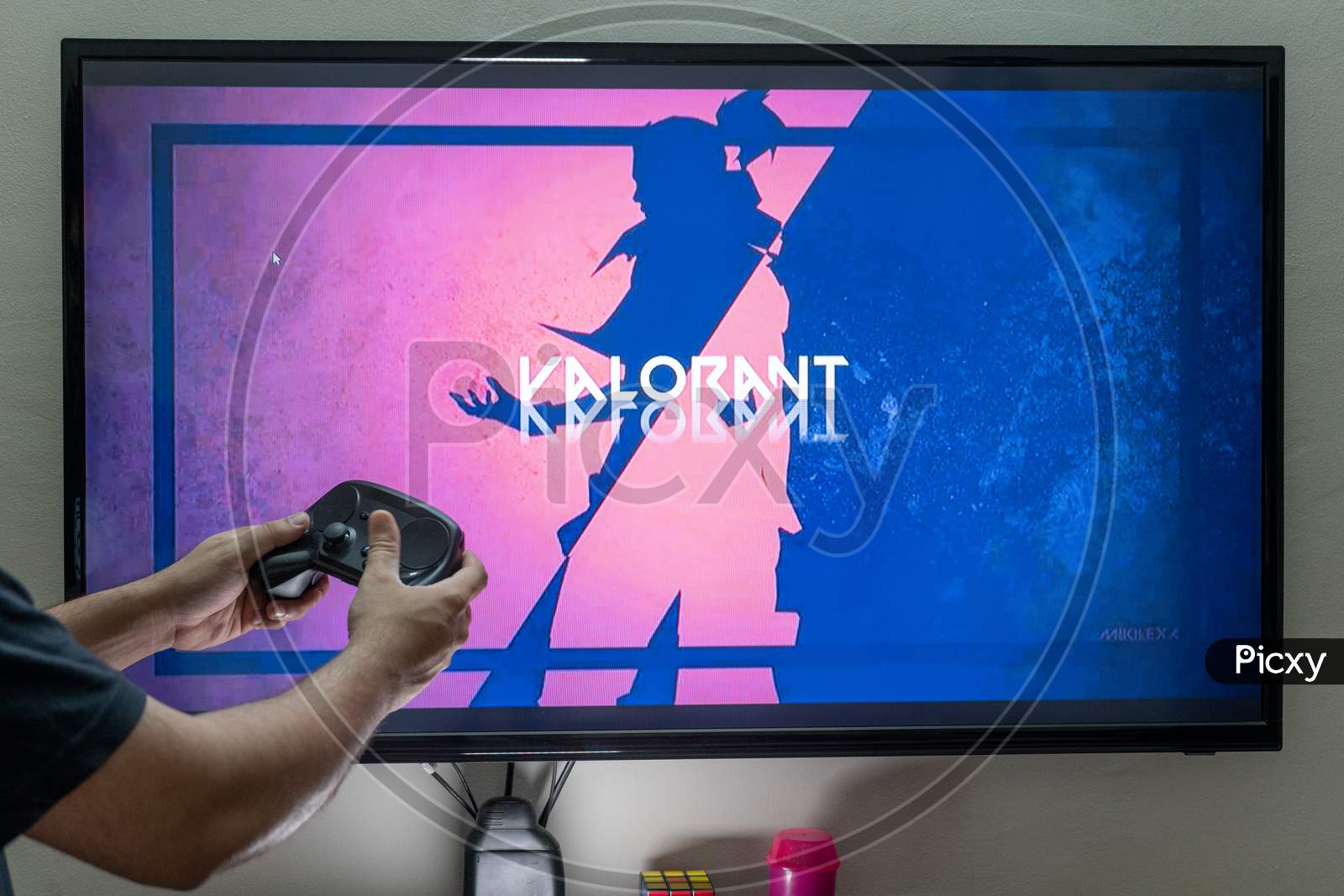 Man Holding Steam Controller In Front Of A Screen Loading Valorant On Pc Console For Gaming Showing This Popular Online Game