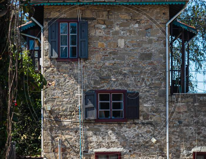 Close-Up A Stone  House With Wooden Windows And Shutters. Old European Architecture