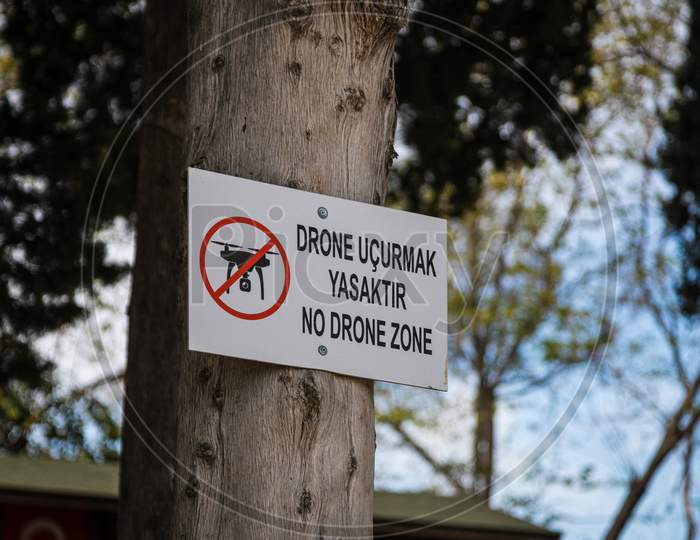 Close-Up Of A Sign With The Translation Rule "No Quadcopters, No Drone Zone" Attached To A Tree